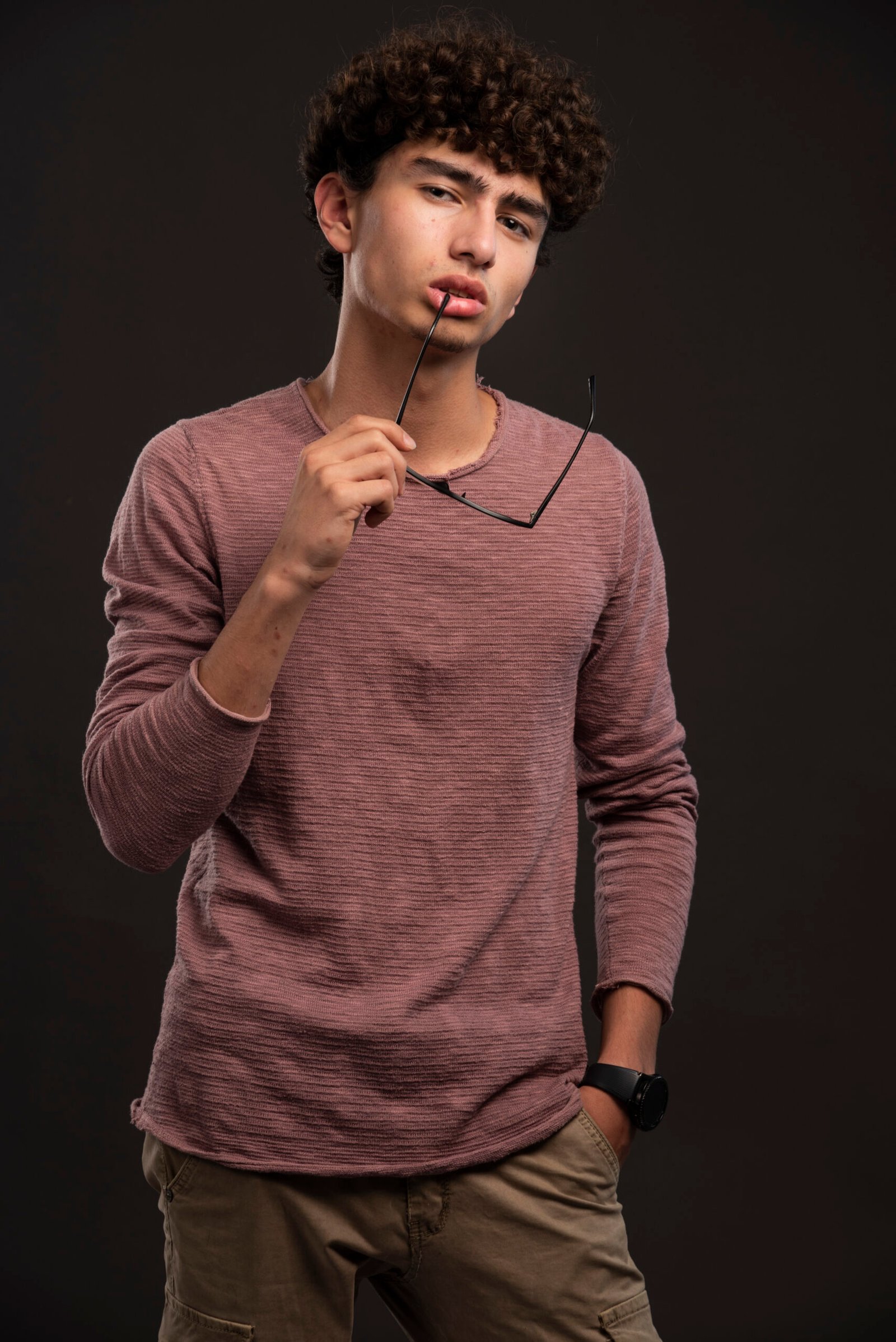 Young boy with curly hairs holding eyeglasses. High quality photo