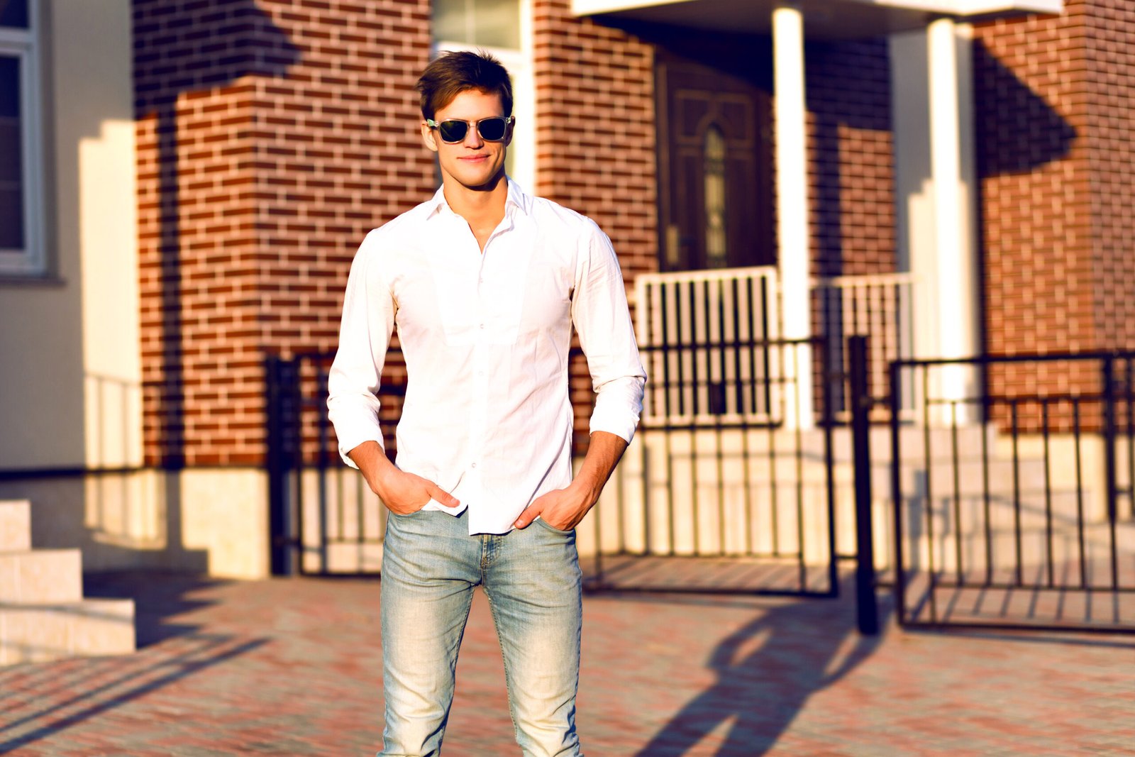 Young hipster man posing on the street, smart casual look, warm sunny toned colors, young businessman walking alone, trendy sunglasses, white shirt.